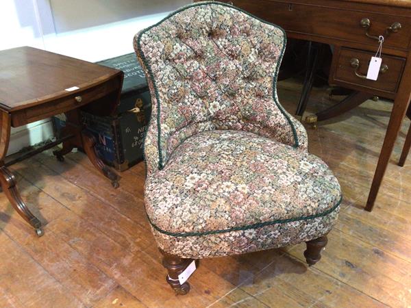 A late Victorian nursing chair in floral upholstery on turned front supports with castors
