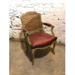 A Louis XV style fauteuil with cane back above a red leather seat and armrests, on cabriole supports