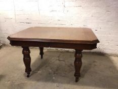 An Edwardian oak dining table, with moulded edge and canted corners, on moulded supports terminating