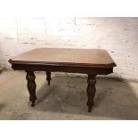 An Edwardian oak dining table, with moulded edge and canted corners, on moulded supports terminating