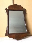 An Edwardian wall mirror, the rectangular glass within a moulded border and carved frame, some