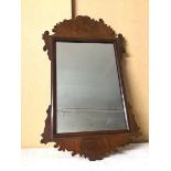An Edwardian wall mirror, the rectangular glass within a moulded border and carved frame, some