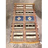 A handwoven rug or wall hanging, with ten flatweave panels divided by stylised flowerhead border,