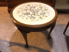 A 1930s circular mahogany occasional table with floral embroidered top under glass, on four cabriole