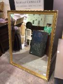 A large contemporary rectangular wall mirror, with bevelled glass within foliate frame (128cm x