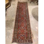 A North West Persian runner, the central panel with a claret red field and repeating floral design