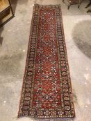 A North West Persian runner, the central panel with a claret red field and repeating floral design