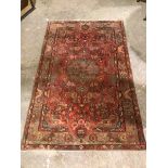 A hamadan rug with central floral medallion surrounded by foliate design, with multiple flowerhead