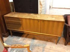 A teak mid century sideboard, with distressed top above four short drawers and two cabinet doors