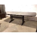 An extendable elm Ercol dining table with three additional leaves, on trestle base with turned
