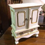 A miniature chest on stand in white painted finish, the top with two doors above three drawers above