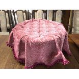 A modern circular footstool the button top pink and sand coloured cover, attached to a stool with