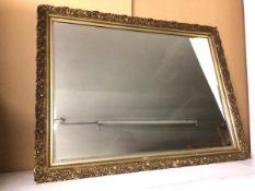 A modern rectangular wall mirror, the bevelled glass within a gilt composition frame with foliate