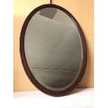 An Edwardian oval wall mirror with bevelled glass within a beaded edge frame (82cm x 57cm)