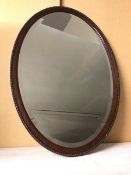 An Edwardian oval wall mirror with bevelled glass within a beaded edge frame (82cm x 57cm)