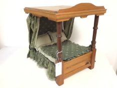 A doll's four poster bed complete with drapes and bedding (40cm x 32cm x 37cm)