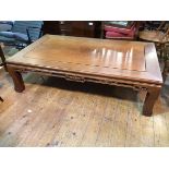 A Chinese low table with chanelled top above a carved apron, on moulded supports (41cm x 149cm x