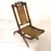 An unusual Continental walnut carved foliate top caned panel back and seat child's folding chair
