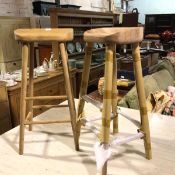 A pair of modern oak bar stools, with saddle seat, on turned supports united by stretchers (82cm x