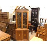 A reproduction yew wood double corner cabinet with broken swan neck pedimented top above a pair of