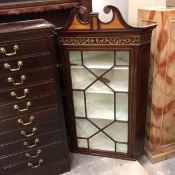 An Edwardian mahogany wall corner cabinet with inlaid swan neck pediment above a glazed astragal