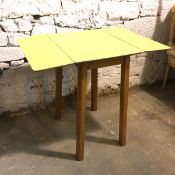 A mid century kitchen table with yellow drop leaf formica top on beech tapering supports (open: 78cm
