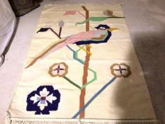 A flatwoven kelim style wall hanging with stylised bird on branch, cream field (182cm x 126cm)