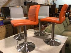 A set of four brushed stainless steel adjustable island stools, upholstered in orange and grey