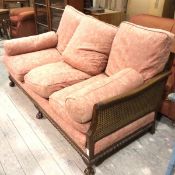 A mahogany double caned bergere three seater sofa with scroll arms and gadroon carved moulded