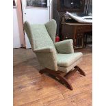 A 1950s/60s sprung wing back rocking chair with scroll arms, in mottled green upholstery (80cm x