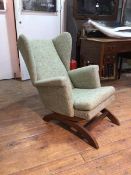 A 1950s/60s sprung wing back rocking chair with scroll arms, in mottled green upholstery (80cm x