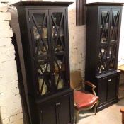 A pair of Oka style black ash upright bookcases with moulded cornices above a pair of glazed