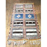 A handwoven rug or wallhanging with ten flat weave panels divided by stylised flowerhead border,