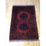 A Khai Muhammedi rug with two stylised flowerhead medallions within multiple borders, red field (