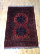 A Khai Muhammedi rug with two stylised flowerhead medallions within multiple borders, red field (