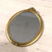 An Edwardian oval gilt wood composition mirror with beaded border and scrolling leaf and floral