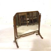 An Edwardian mahogany swing mirror with shaped glass on square end supports, complete with acorn