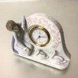 A Spanish Lladro quartz clock with Seated Figure and Two Swans, decorated with polychrome enamels (