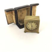 A Zenith Swiss made alarm clock with engine turned brass case and gilt dial with arabic numerals,