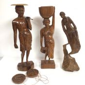 A group of three carved Malaysian style figures, one carrying a basket, the other with two