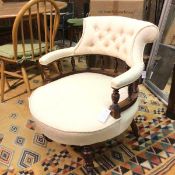 An Edwardian horseshoe shaped button back, upholstered arm and seat tub chair, raised on turned