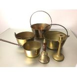 A brass bell, a brass candlestick, a brass saucepan with cast iron handle, three various brass