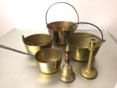 A brass bell, a brass candlestick, a brass saucepan with cast iron handle, three various brass
