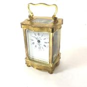 A French reproduction brass serpentine cased four glass clock with enamelled dial and roman