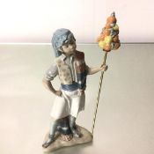 A Spanish Lladro porcelain figure, The Fruit Seller, dressed in Arabic attire, with brass rod and