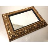 A 1920s compressed moulded paper rectangular framed wall mirror with ebonised painted slip and