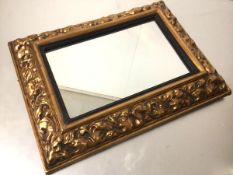 A 1920s compressed moulded paper rectangular framed wall mirror with ebonised painted slip and