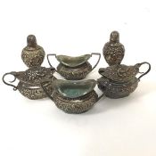 A six piece Birmingham silver chased oval condiment set comprising two pepperettes, two salt cellars