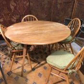 An Ercol elm oval drop leaf dining table and set of four spar back chairs with padded seats and