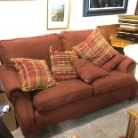 A modern two seater sofa with walnut frame upholstered in terracotta tweed style fabric, complete